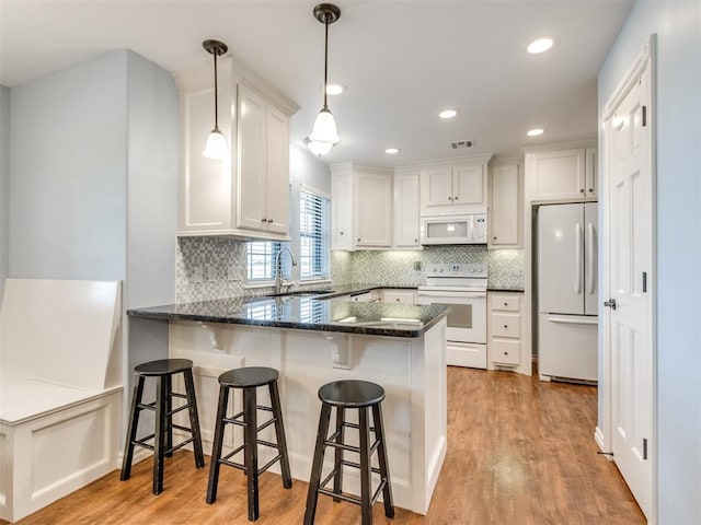 1616 E Cottonwood Rd, Goldsby, OK 73093 - kitchen featuring white appliances, a peninsula, light wood-style floors, dark stone countertops, and white cabinets