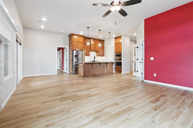9233 NW 91st St, Yukon, OK 73099 - kitchen featuring appliances with stainless steel finishes, open floor plan, a ceiling fan, recessed lighting, and brown cabinetry