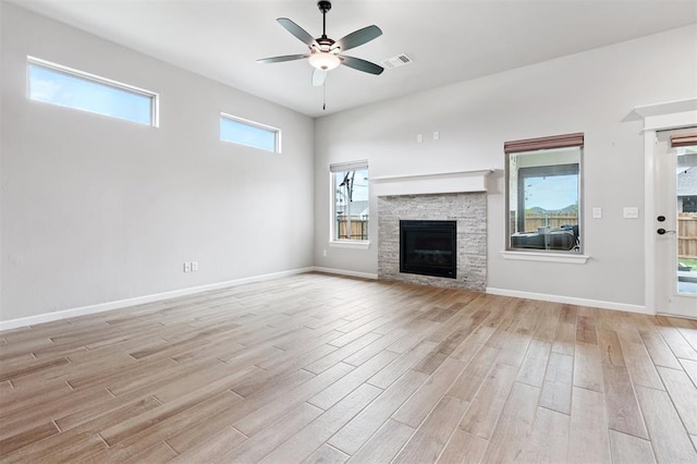 9233 NW 91st St, Yukon, OK 73099 - unfurnished living room with light wood-type flooring, ceiling fan, healthy amount of natural light, and a stone fireplace