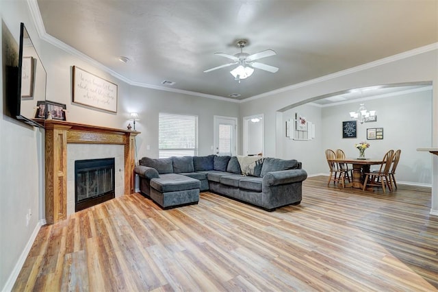 2209 Cedar Pointe Ct, Edmond, OK 73003 - living area with light wood-style flooring, a chandelier, a tiled fireplace, ceiling fan, and arched walkways