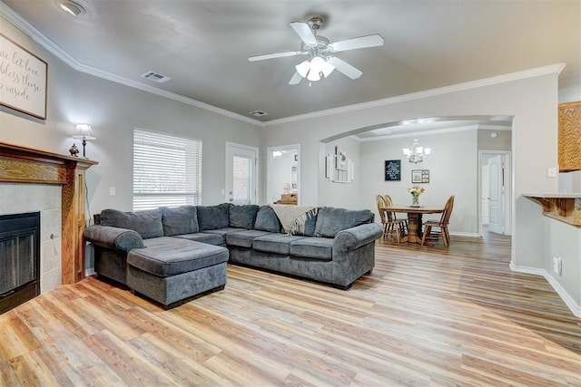2209 Cedar Pointe Ct, Edmond, OK 73003 - living room with light wood finished floors, arched walkways, ceiling fan, ornamental molding, and a tiled fireplace