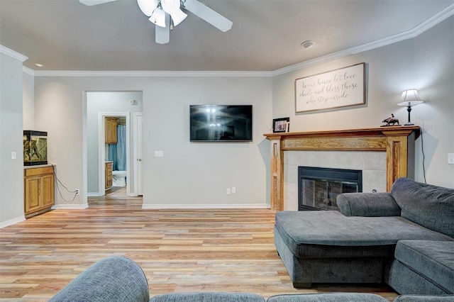 2209 Cedar Pointe Ct, Edmond, OK 73003 - living room with a ceiling fan, crown molding, light wood-style floors, and a tile fireplace