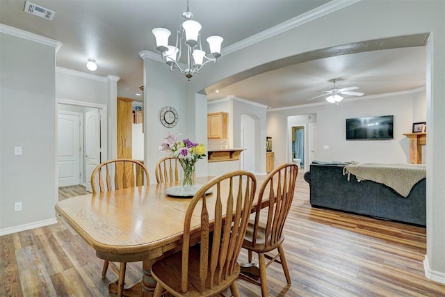 2209 Cedar Pointe Ct, Edmond, OK 73003 - dining room featuring light wood-style floors, arched walkways, crown molding, a chandelier, and ceiling fan