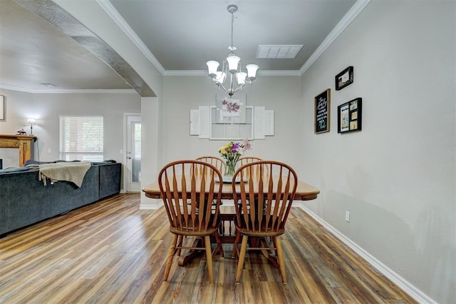 2209 Cedar Pointe Ct, Edmond, OK 73003 - dining room with wood finished floors, arched walkways, ornamental molding, and a chandelier