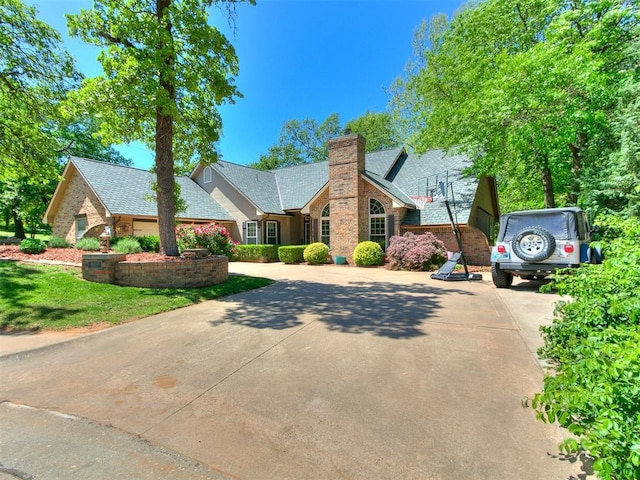 402 Hunters Ct, Edmond, OK 73034 - view of front of home with concrete driveway, a chimney, brick siding, and a front lawn