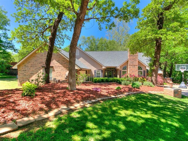 402 Hunters Ct, Edmond, OK 73034 - view of front of home featuring a front lawn, brick siding, and a chimney
