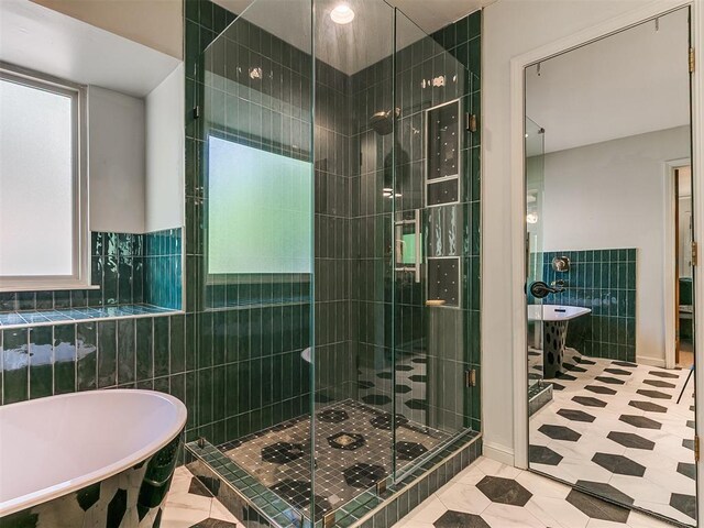 402 Hunters Ct, Edmond, OK 73034 - bathroom featuring tile walls, a freestanding tub, a stall shower, and tile patterned floors