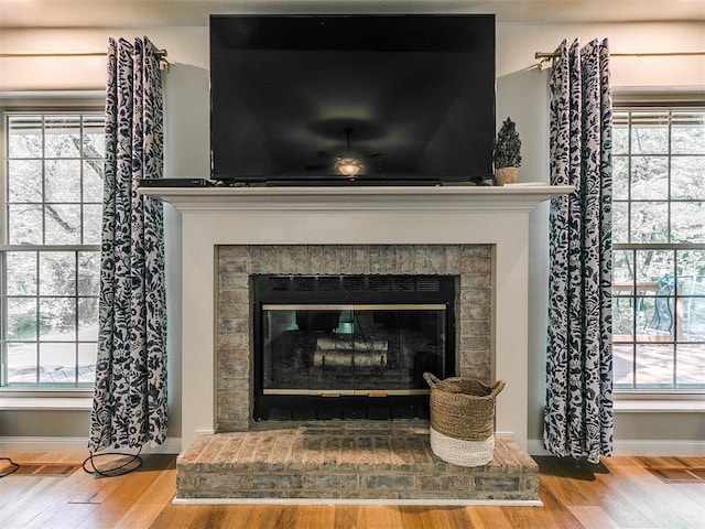 402 Hunters Ct, Edmond, OK 73034 - detailed view of a glass covered fireplace, wood finished floors, and ceiling fan