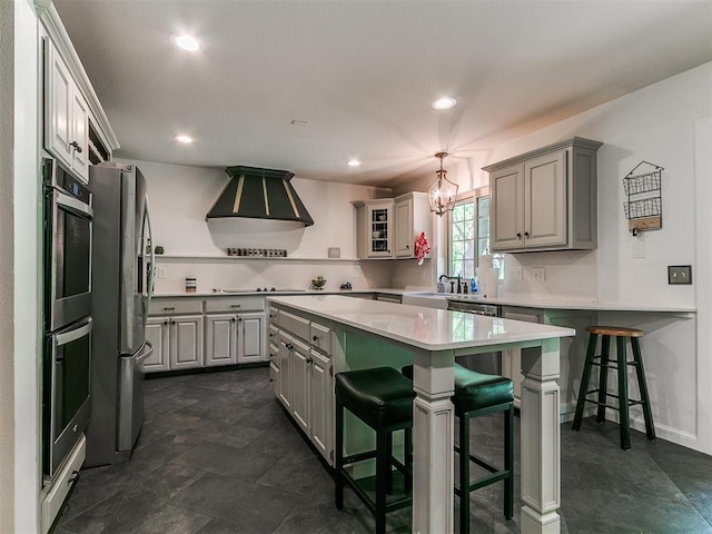 402 Hunters Ct, Edmond, OK 73034 - kitchen featuring appliances with stainless steel finishes, gray cabinets, light countertops, a kitchen bar, and recessed lighting
