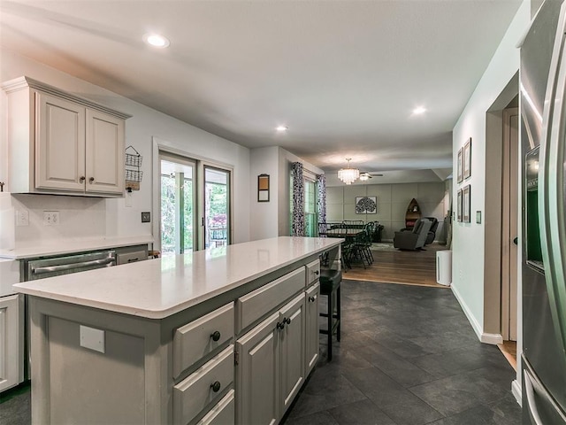 402 Hunters Ct, Edmond, OK 73034 - kitchen featuring gray cabinets, a kitchen island, open floor plan, recessed lighting, and a breakfast bar