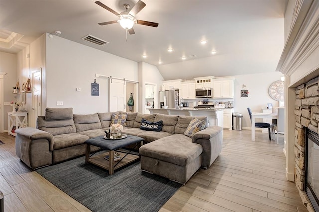 4004 Brougham Way, Oklahoma City, OK 73179 - living room featuring a barn door, a ceiling fan, light wood-style floors, vaulted ceiling, and a fireplace