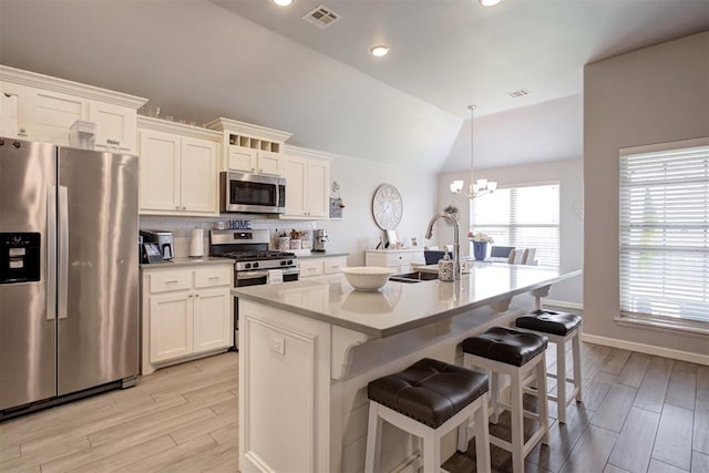 4004 Brougham Way, Oklahoma City, OK 73179 - kitchen featuring appliances with stainless steel finishes, light wood-style flooring, a chandelier, a kitchen island with sink, and lofted ceiling