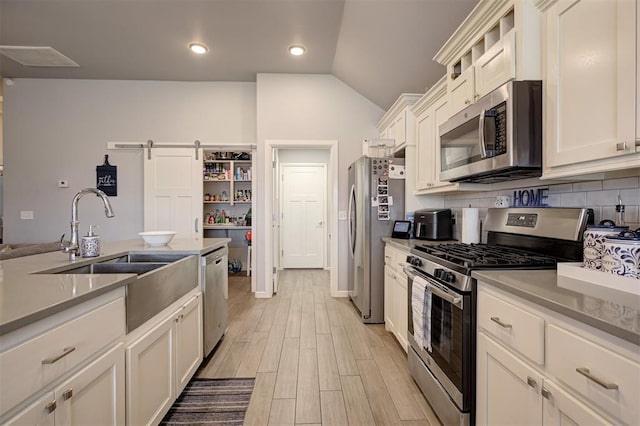4004 Brougham Way, Oklahoma City, OK 73179 - kitchen featuring stainless steel appliances, white cabinets, light wood-style floors, vaulted ceiling, and backsplash
