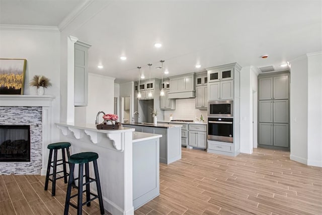 4204 Chesterfield Pl, Oklahoma City, OK 73179 - kitchen with appliances with stainless steel finishes, a peninsula, wood finish floors, a kitchen bar, and crown molding