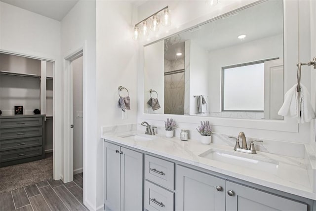 4204 Chesterfield Pl, Oklahoma City, OK 73179 - bathroom featuring double vanity, wood finish floors, tiled shower, and a spacious closet