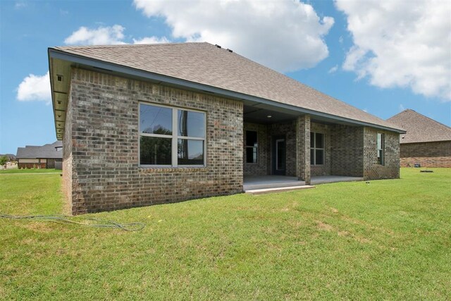 4204 Chesterfield Pl, Oklahoma City, OK 73179 - rear view of property featuring brick siding, a lawn, a patio area, and roof with shingles
