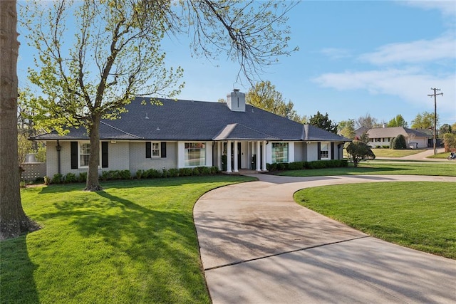 ranch-style house with curved driveway, a front lawn, and a chimney
