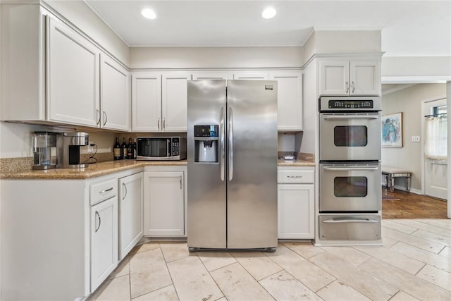 kitchen with appliances with stainless steel finishes, a warming drawer, white cabinetry, crown molding, and recessed lighting