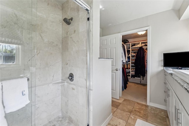 bathroom featuring vanity, a shower stall, and a walk in closet