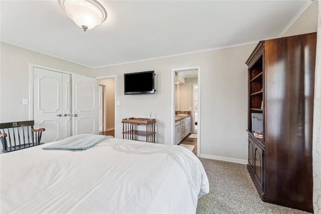 carpeted bedroom featuring crown molding, ensuite bathroom, and a closet
