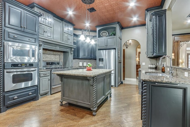 405 Kingsgate Rd, Yukon, OK 73099 - kitchen featuring appliances with stainless steel finishes, arched walkways, decorative backsplash, light stone countertops, and light wood-style flooring