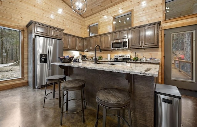 944 Camp Ranch Rd, Broken Bow, OK 74728 - kitchen featuring stainless steel appliances, high vaulted ceiling, concrete flooring, light stone counters, and wooden walls