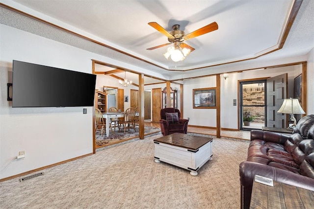 2408 Shady Tree Ln, Edmond, OK 73013 - carpeted living area featuring a raised ceiling, a chandelier, and a ceiling fan