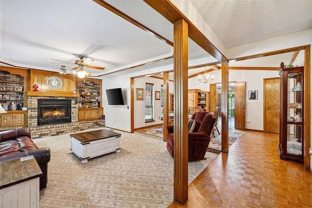 2408 Shady Tree Ln, Edmond, OK 73013 - living room featuring ceiling fan, a chandelier, a fireplace, built in shelves, and a textured ceiling