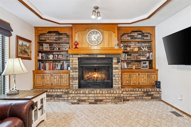 2408 Shady Tree Ln, Edmond, OK 73013 - carpeted living area featuring built in features, a fireplace, and a raised ceiling