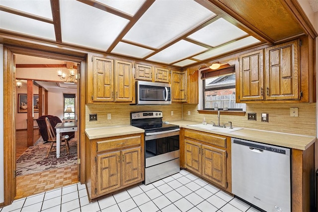 2408 Shady Tree Ln, Edmond, OK 73013 - kitchen with stainless steel appliances, light countertops, decorative backsplash, and brown cabinets