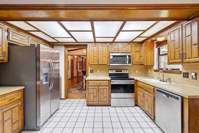 2408 Shady Tree Ln, Edmond, OK 73013 - kitchen featuring stainless steel appliances, decorative backsplash, light countertops, and brown cabinetry