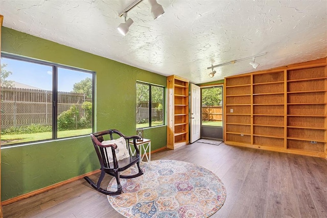 2408 Shady Tree Ln, Edmond, OK 73013 - sitting room featuring track lighting, wood finished floors, a textured wall, and a textured ceiling