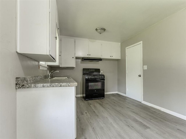3320 NE 14th St, Oklahoma City, OK 73117 - kitchen with black range with gas stovetop, light wood-type flooring, white cabinetry, light countertops, and under cabinet range hood