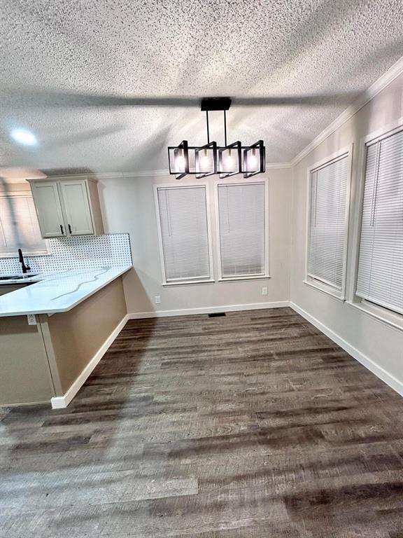 13001 Fox Pass Rd, Edmond, OK 73034 - unfurnished dining area with a chandelier, crown molding, a textured ceiling, and dark wood-type flooring