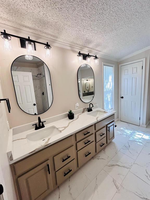 13001 Fox Pass Rd, Edmond, OK 73034 - full bathroom with double vanity, ornamental molding, a textured ceiling, a shower, and marble finish flooring