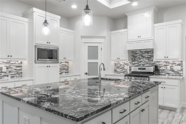 8908 NW 130th St, Oklahoma City, OK 73142 - kitchen with stainless steel range oven, built in microwave, a center island with sink, decorative backsplash, and recessed lighting