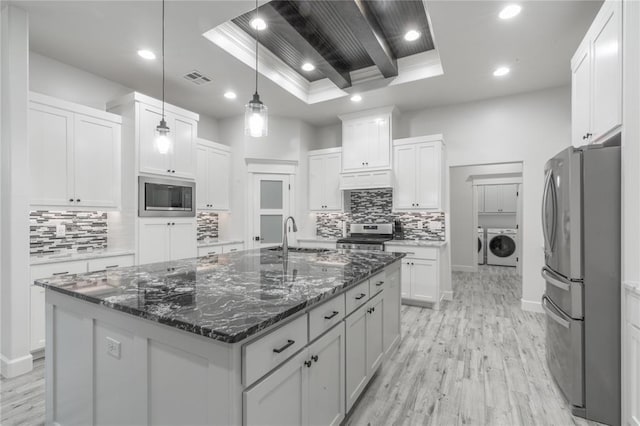 8908 NW 130th St, Oklahoma City, OK 73142 - kitchen featuring stainless steel appliances, a raised ceiling, washing machine and dryer, light wood-type flooring, and recessed lighting