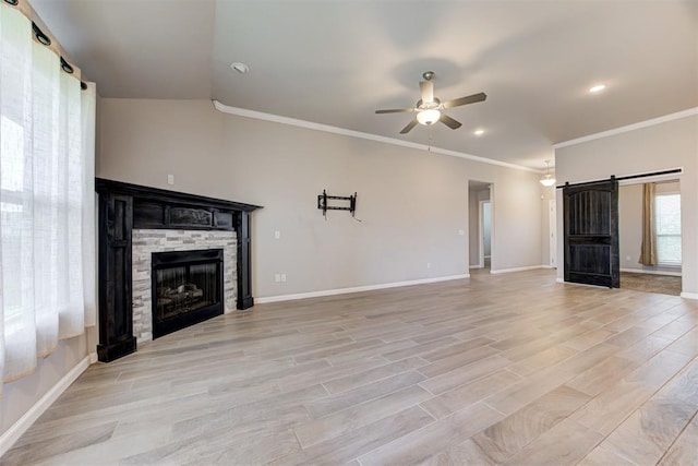 4213 NW 155th St, Edmond, OK 73013 - unfurnished living room with a ceiling fan, a stone fireplace, crown molding, a barn door, and light wood-style flooring