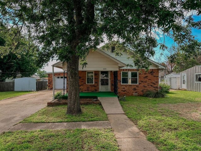 309 N Spencer Ave, Hinton, OK 73047 - view of front of house with a shed, concrete driveway, brick siding, and a garage