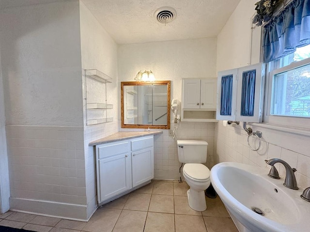 309 N Spencer Ave, Hinton, OK 73047 - bathroom with tile patterned floors, tile walls, a textured ceiling, and a wainscoted wall