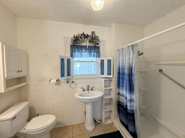 309 N Spencer Ave, Hinton, OK 73047 - bathroom with tile patterned flooring, a shower stall, tile walls, a textured ceiling, and wainscoting