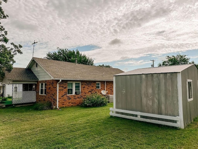 309 N Spencer Ave, Hinton, OK 73047 - rear view of property featuring a shed, a lawn, brick siding, and a shingled roof