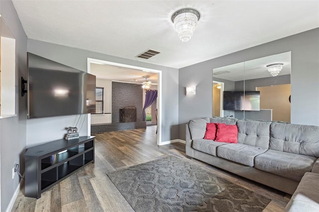 8316 NW 39th St, Bethany, OK 73008 - living area featuring wood finished floors, a brick fireplace, a ceiling fan, and a chandelier