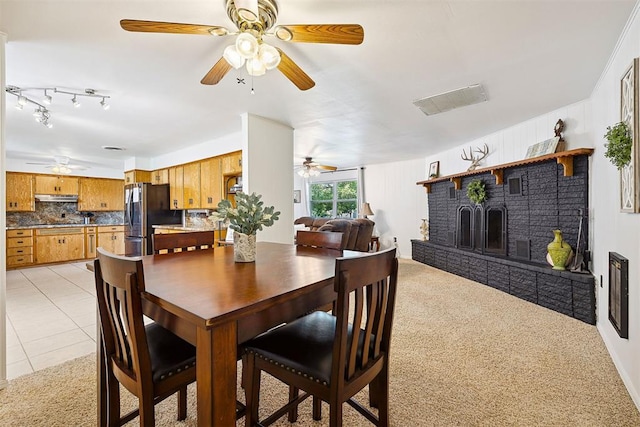 213 Meadowlark Ln, Fort Cobb, OK 73038 - dining area with a ceiling fan, a brick fireplace, light tile patterned floors, and light colored carpet