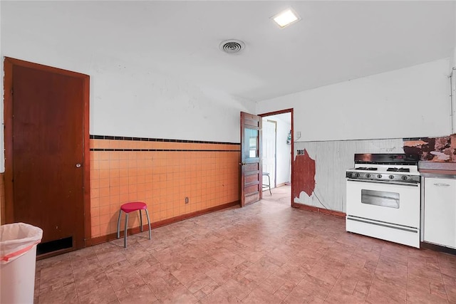 105 E E Walk, Canute, OK 73626 - kitchen with white gas stove, a wainscoted wall, and white cabinets