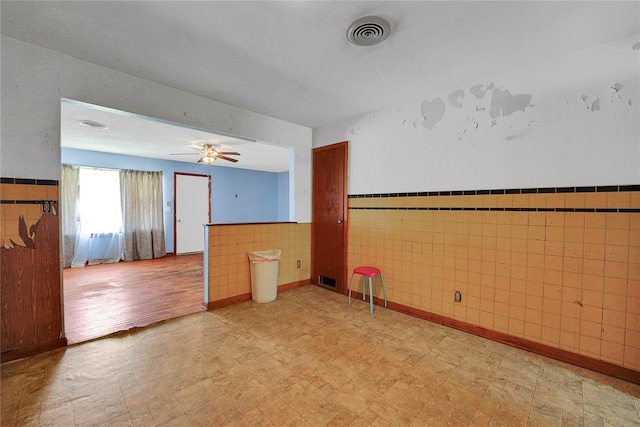 105 E E Walk, Canute, OK 73626 - spare room with light floors, tile walls, a wainscoted wall, and a ceiling fan
