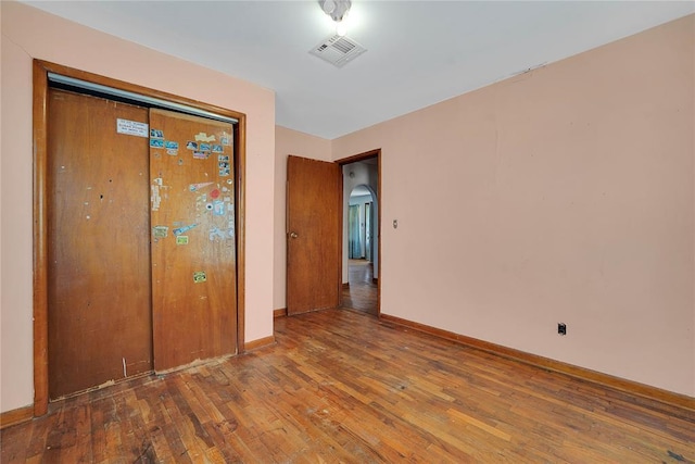 105 E E Walk, Canute, OK 73626 - unfurnished bedroom featuring hardwood / wood-style flooring, arched walkways, and a closet