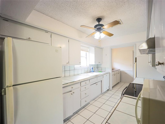 516 SW 63rd Ter, Oklahoma City, OK 73139 - kitchen featuring white appliances, tile counters, white cabinets, a textured ceiling, and exhaust hood