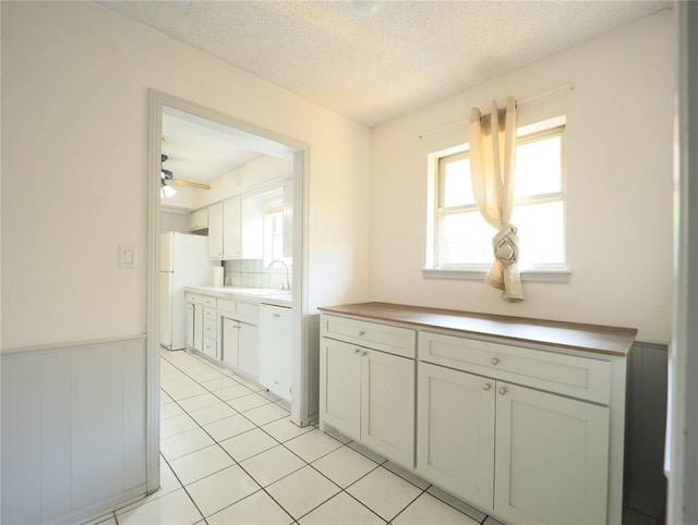 516 SW 63rd Ter, Oklahoma City, OK 73139 - kitchen with white appliances, a textured ceiling, ceiling fan, a wainscoted wall, and light tile patterned floors