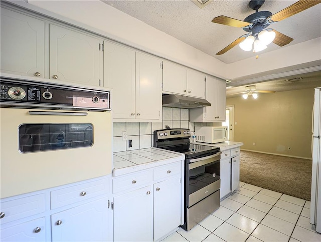 516 SW 63rd Ter, Oklahoma City, OK 73139 - kitchen featuring white appliances, under cabinet range hood, a ceiling fan, tile countertops, and white cabinetry